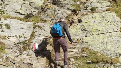 Male-hiker-climbs-along-GR-path-on-mountainside,-Italy