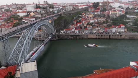 Aerial-view-of-a-boat-on-River-Douro-near-Luis-I-Bridge-on-scenic-day-in-Portugal