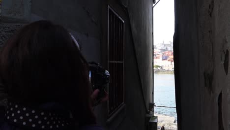 Woman-taking-photos-of-the-old-town-of-Porto-standing-in-dark-alley