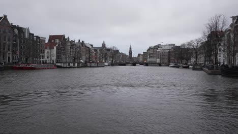 Big-Amsterdam-city-canal,-urban-landscape-with-scenic-dutch-architectural-buildings-and-docked-houseboats
