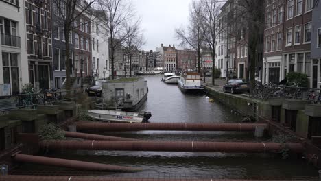 Scenic-shot-of-canal-in-Amsterdam-with-pipelines-going-through-the-neighbourhood-with-dutch-architectural-buildings