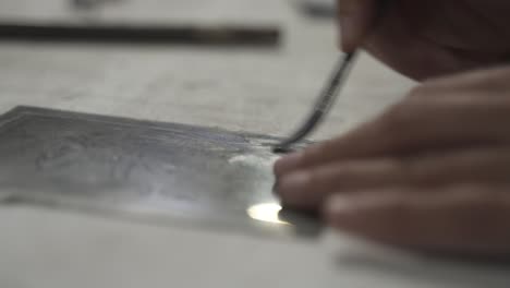 Close-up-shot-of-artistic-hand-made-during-engraving-process-using-transfer-plate,-artwork-in-studio