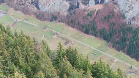 Far-view-of-rescue-helicopter-fly-through-green-Switzerland-mountain-valley