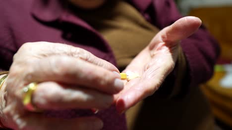 Elderly-hands-holding-pills-and-checking,-contemplating-medication