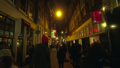 Tourists-walking-around-the-busy-night-streets-in-Amsterdam,-nightlife