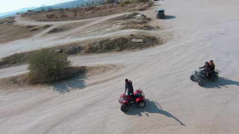 Tour-En-Vehículos-Todo-Terreno-En-Capadocia:-Un-Hombre-Aventurero-Saluda-A-La-Cámara-De-Un-Dron-Mientras-Está-De-Pie-En-Un-Quad-En-Turquía