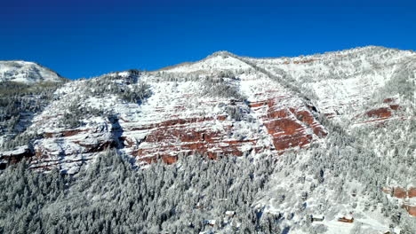 Imágenes-De-Drones-Volando-Hacia-Un-Acantilado-De-Roca-Roja-Gigante-Cubierto-De-Nieve-Ubicado-En-Las-Montañas-Rocosas-De-Colorado