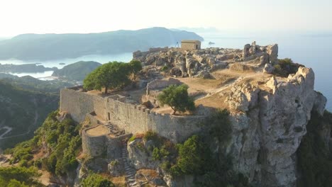 Dramatic-Angelokastro-fortress-ruins,-breathtaking-Corfu-coast-AERIAL-ORBITAL