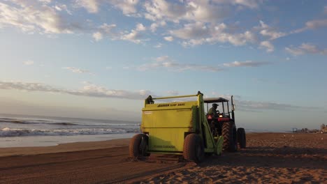 Sandtraktor-Glättet-Die-Reinigung-Des-Strandes,-Die-Skyline-Des-Atlantischen-Ozeans-Am-Morgen-Des-Sonnenaufgangs
