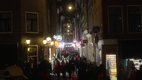 Busy-city-street-near-the-red-light-district-in-Amsterdam,-tourists-and-pedestrians-walking-busy-street