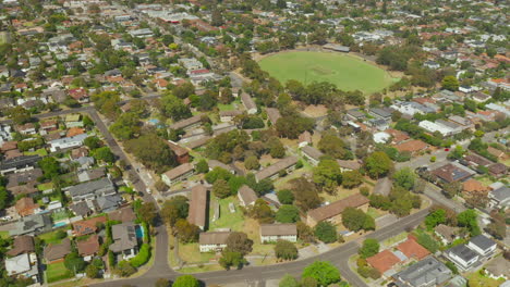 In-an-aerial-spiral-camera-movement-revealing-the-suburban-houses-and-two-vast-football-fields
