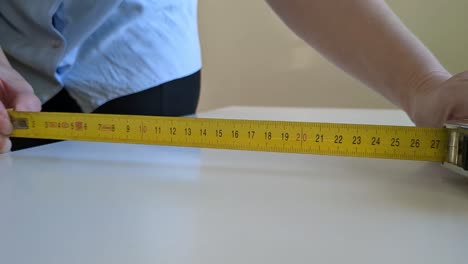 Woman-using-tape-measure-for-measuring-surface,-close-up