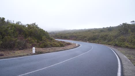 View-of-a-road-in-the-mountains-of-madeira-island-during-winter,-fog-covering-a-section-of-the-road