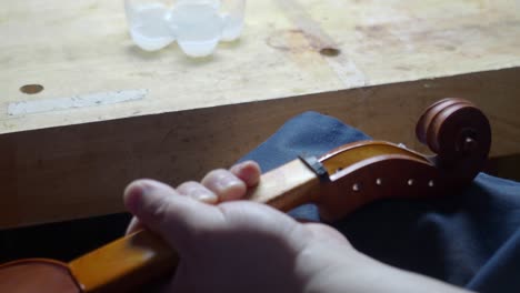Geigenbaumeister-Und-Geigenbauer-Antiquieren-Die-Locken-Der-Geige-Und-Den-Wirbelkasten-Mit-Einem-Tuch-Und-ätzendem-Öl-Auf-Einem-Neuen-Saiteninstrument,-Um-Die-Ursprüngliche-Not-Des-Meisterwerks-Zu-Reproduzieren