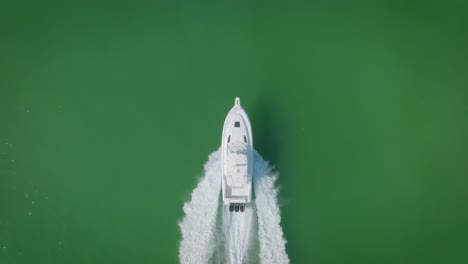 A-yacht-gracefully-sails-through-the-green-sea-off-the-coast-of-Miami,-where-white-waves-break-against-its-hull