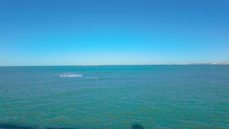 calm-and-expansive-ocean-view-under-a-clear-blue-sky,-with-gentle-waves-and-a-distant-horizon,-evoking-a-sense-of-peace-and-vastness