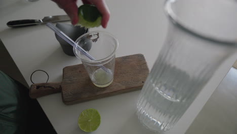 Hand-squeezing-lime-into-water-on-rustic-kitchen-board