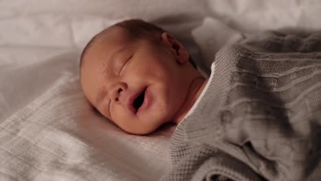 Cute-newborn-baby-boy-yawning-and-falling-asleep-on-sofa-in-living-room