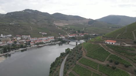 Aerial-view-of-the-old-bridge-over-the-Douro-river-in-Pinhão,-Drone-rotating-to-the