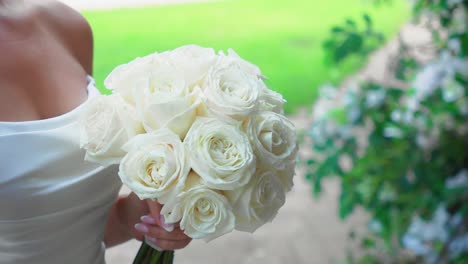 Closeup-shot-of-the-white-bridal-bouquet-with-white-roses-in-the-hands-of-a-beautiful-bride-outdoor-on-a-wedding-day