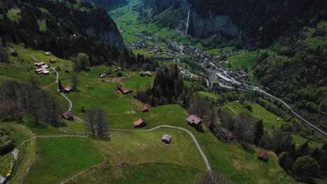 Disparo-De-Un-Dron-Que-Revela-El-Pueblo-De-Lauterbrunnen-Y-La-Cascada-De-Staubbach,-La-Cascada-Más-Alta-De-Suiza,-Tomada-Desde-El-Pueblo-De-Wengen-Con-Las-Montañas-Nevadas-De-Los-Alpes-Suizos-Al-Fondo