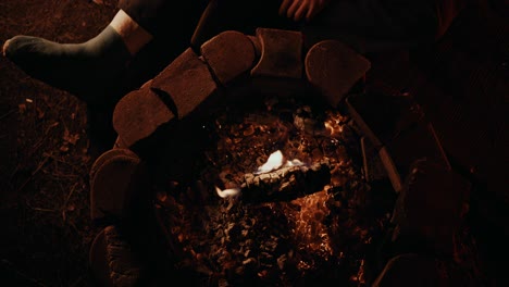 Campfire-Coffee:-young-man-with-his-broken-leg-in-a-blue-cast-straightens-the-last-big-chunk-of-wood-in-his-campfire-using-the-trusty-old-knife-he-brought