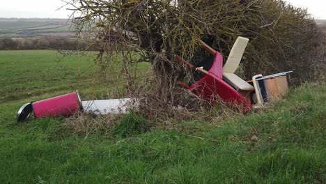 Office-furniture-illegally-fly-tipped-into-a-hedge-on-a-uk-rural-roadside