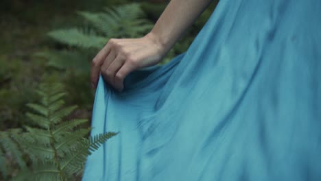 Mujer-Sosteniendo-Su-Vestido-Azul-Caminando-Por-El-Bosque-Como-Un-Hada,-De-Cerca