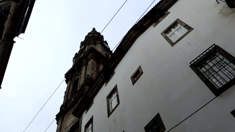 Low-angle-orbit-of-Torre-dos-Clerigos-from-a-Porto-alley,-Portugal