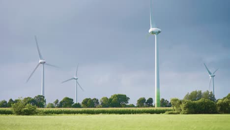 Riesige-Rotierende-Windkraftanlagen-In-Der-üppigen-Grünen-Landschaft