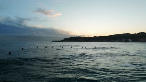 Group-of-surfers-waiting-for-wave-at-sunset,-Varazze,-Liguria-in-Italy