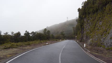 View-of-a-road-carved-in-the-mountains-of-madeira-island-during-winter,-fog-covering-a-section-of-the-road