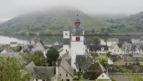 Small-German-town-on-a-river-in-a-valley-in-the-fog-between-two-wooded-hills-with-a-lot-of-thick-fog,-on-the-Moosel-in-Germany