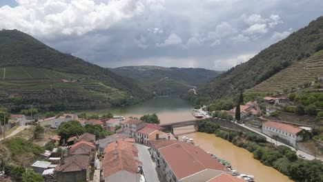 Aerial-view-of-the-wine-town-of-Pinhão-Portugal-,-Drone-moving-forward-over-the-roof-houses-showing-the-Pinhão-river-on-the-right-joining-the-Douro-river