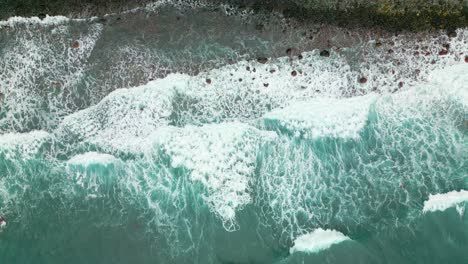 Gigantic-waves-reaching-rocky-shoreline-of-Madeira-Island-during-sunny-day---Aerial-top-down