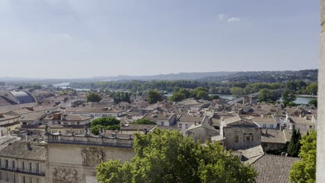 Panning-over-French-town-with-many-old-stone-houses-and-historic-buildings-and-churches-in-good-weather-and-balmy-sky-and-green-hills-on-the-horizon