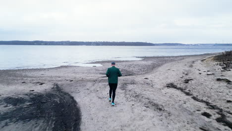 Lone-person-jogging-on-a-desolate-winter-beach-on-overcast-day