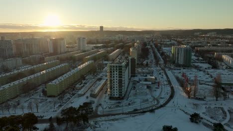 he-warm-glow-of-the-sunset-bathes-a-snowy-urban-landscape,-with-residential-buildings-and-roads-etched-into-the-winter-scene,-showcasing-a-blend-of-nature-and-city-life-in-city-Gdańsk