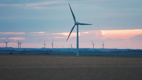 Reihen-Von-Windkraftanlagen-Auf-Den-Feldern-Unter-Dem-Blassen-Sonnenuntergangshimmel