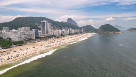 High-angle-aerial-dolly-view-over-famous-Copacabana-beach-with-beachgoers,-Rio