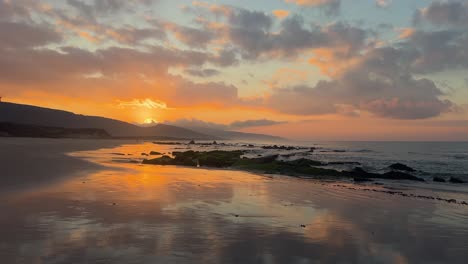 Wellen,-Die-Während-Eines-Perfekten-Sonnenuntergangs-An-Einem-Ruhigen-Strand-In-Felsen-Rollen