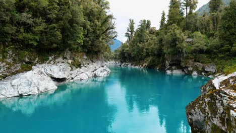 Spectacular-wide-shot-capturing-the-dynamic-flow-of-water-through-Hokitika-Gorge,-a-mesmerizing-display-of-nature's-power