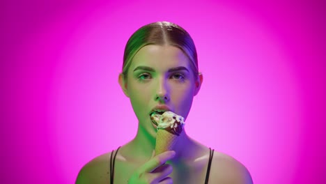 Young-Blonde-Caucasian-woman-eats-ice-cream-in-a-studio-with-infinite-background