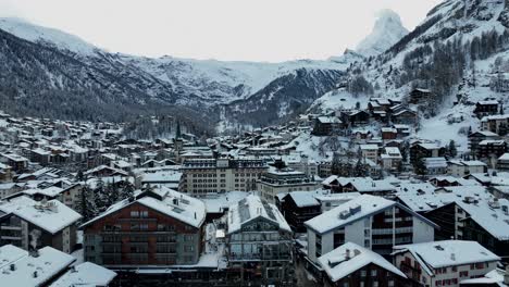 Slow-drone-rising-up-over-the-town-of-Zermatt,-Switzerland-on-a-winter-day