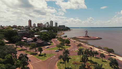 Drone-advancing-over-the-Costanera-Avenue-of-Posadas,-showcasing-monuments-and-the-city's-skyline