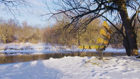 Foto-De-Perfil-De-Un-Banco-Junto-A-Un-Lago-Congelado-Con-árboles-Cubiertos-De-Nieve-A-Su-Alrededor.
