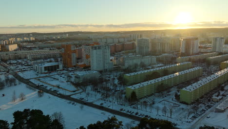 Goldene-Stunde-über-Einer-Schneebedeckten-Stadtlandschaft-Mit-Einem-Herausragenden-Orangefarbenen-Gebäude-Inmitten-Einheitlich-Gefärbter-Wohnungen,-Die-Das-Verblassende-Sonnenlicht-Reflektieren-–-Danzig