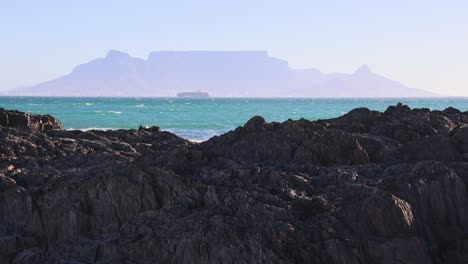 Fernsicht-Auf-Den-Tafelberg-Mit-Meereswellen-Auf-Felsen