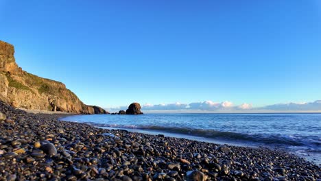 Slowmotion-wet-pebble-beach-calm-seas-and-blue-sky-Copper-Coast-Waterford-Ireland