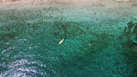 Aerial-top-down-drone-shot-of-a-paddle-boarders-in-turquoise-aegean-sea-,-beach-of-Andros,-Cyclades,-Greece